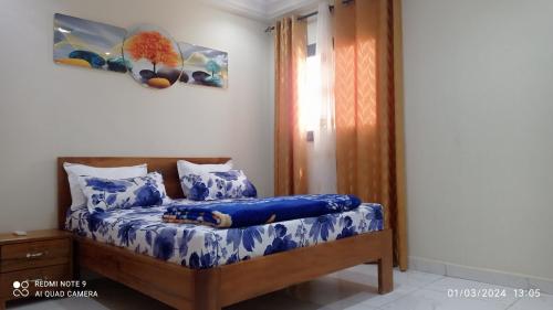 圣路易斯Chez Mamanta Studio meublé à St louis的一间卧室配有一张带蓝色床单的床和一扇窗户。