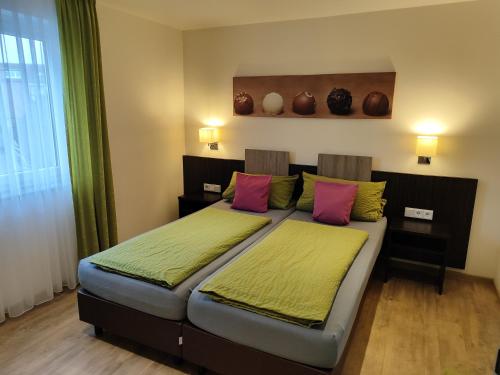 腓特烈港Hotel Stock Trüffeleckle的一间卧室配有带粉色和绿色枕头的床