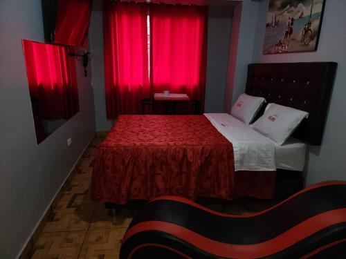 利马hostal paris的一间卧室配有红色窗帘和一张红色毯子