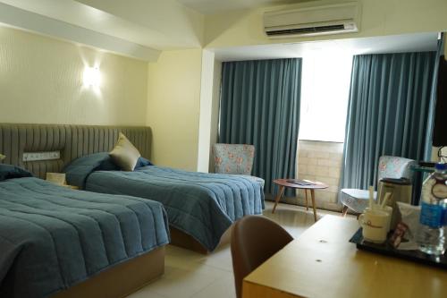 孟买Hotel Diplomat, Colaba的酒店客房设有两张床和一张桌子。