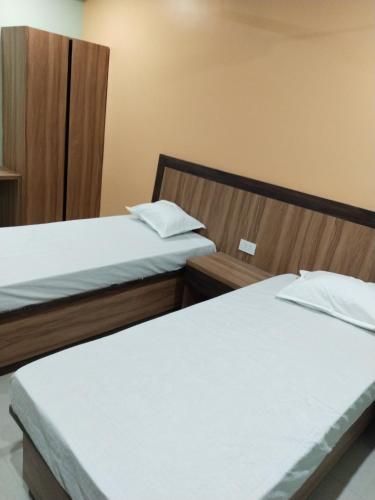 MadhubaniHotel Jyoti的配有白色床单的酒店客房内的两张床