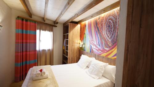 普拉加德阿罗EL DELFÍN VERDE RESORTS - Platja d'Aro的卧室配有一张白色床,墙上挂有绘画作品