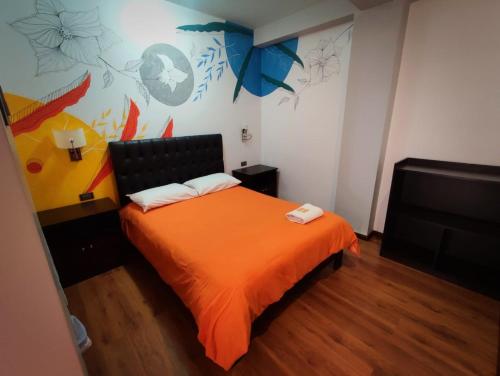 库斯科Magic Packer Hostel的一间卧室配有一张带橙色毯子的床