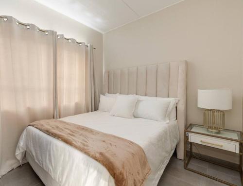 米德兰Waterfall Ridge - Retreat in the heart of Midrand的白色卧室设有一张大床和一盏灯。