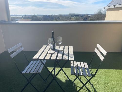 朗西厄Studio avec terrasse proche de la mer的阳台配有桌子和两把椅子及酒杯