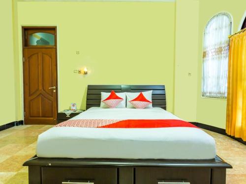 马塔兰Senaz Guesthouse的一间卧室配有一张带红色枕头的大床