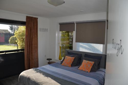 巴勒哈姆斯泰德B&B Onder de Molen的一间卧室配有带橙色枕头的床和窗户。