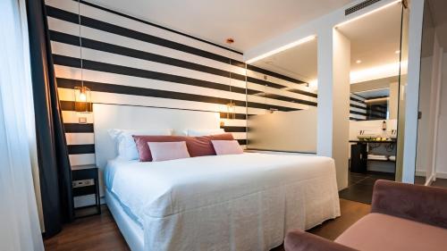 里斯本Hills Hotel Lisboa的卧室配有白色的床和条纹墙
