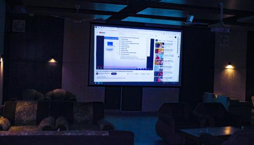 ChirāwaSangam Hotel Marriage Garden & Restaurant的椅子房间里一个大投影屏幕