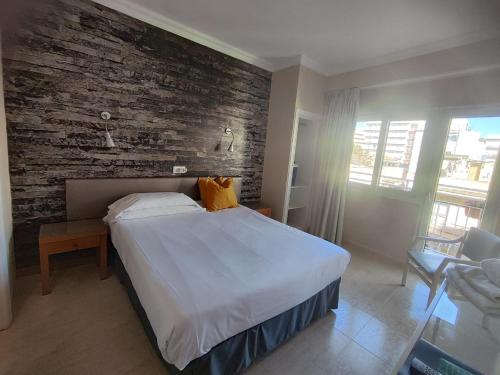 埃尔阿雷纳尔银海旅馆的一间卧室设有一张大床和砖墙