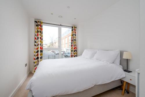 伦敦GuestReady - Modern lodge with garden的白色的卧室设有一张大床和一个窗户