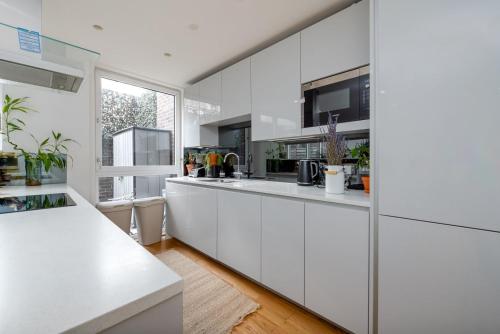 伦敦GuestReady - Modern lodge with garden的白色的厨房配有白色橱柜和窗户