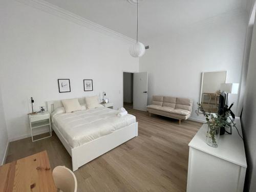 马拉加Suites Larios的白色卧室配有床和沙发