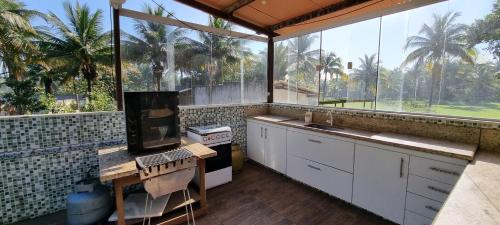 瓜拉派瑞Maravilhoso Recanto Santa Rosa的户外厨房设有棕榈树大窗户