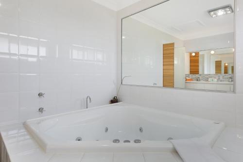 黄金海岸Magnificent 4-Bed Waterfront With Pool & Views的白色的浴室设有浴缸和大镜子