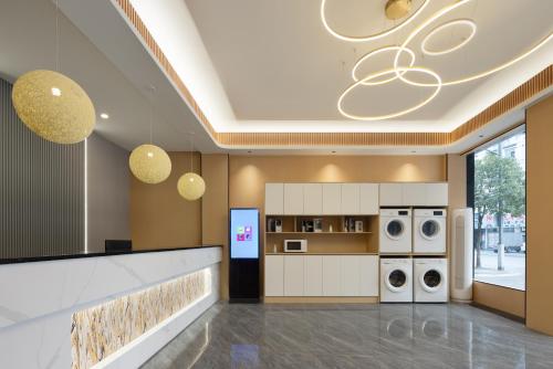 婺源Anlan Hotel Shangrao Wuyuan Cultural Plaza的大楼内带洗衣机和烘干机的厨房