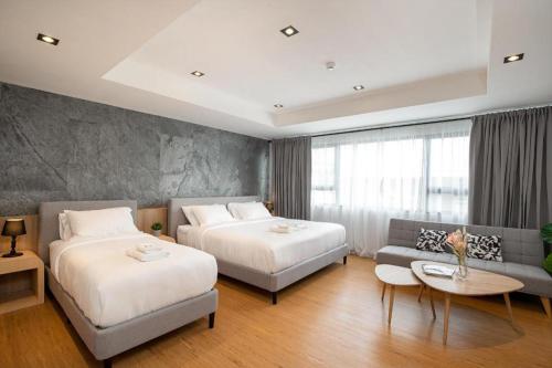 曼谷INFINITE HOTEL @KASET的酒店客房,设有两张床和一张沙发