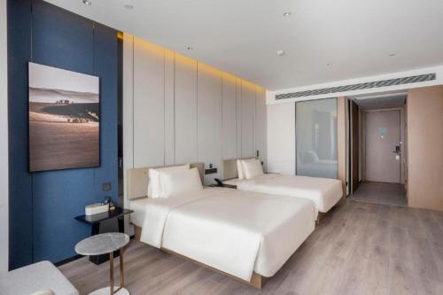 滨海新区Atour Hotel Tianjin Shengtaicheng Maritime Museum的一间卧室设有两张床和蓝色的墙壁