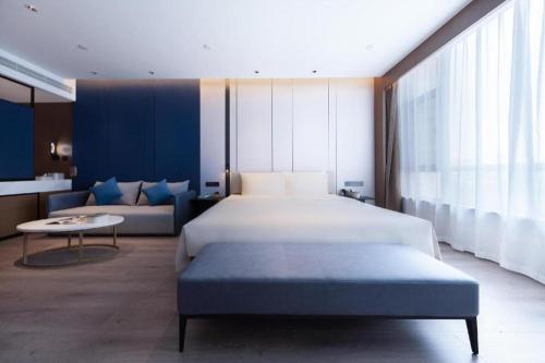 济南Atour Hotel Jinan Tangyan Dongbaqu Enterprise Park的一间卧室配有一张大床和一张沙发