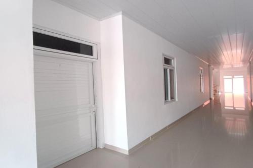 BanualuhuOYO 92504 Guesthouse Porsea的白色的房间,设有车库门和窗户