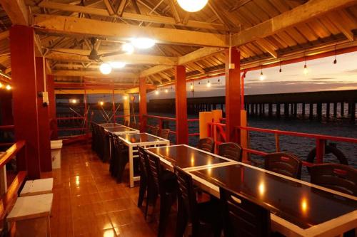 丹戎槟榔Sunset Curly Bay Hotel & Resort的船上的酒吧,配有桌椅