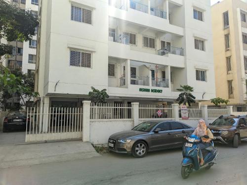 辛加瓦迪Akshra residency 1 bhk的一名在建筑物前骑摩托车的女人