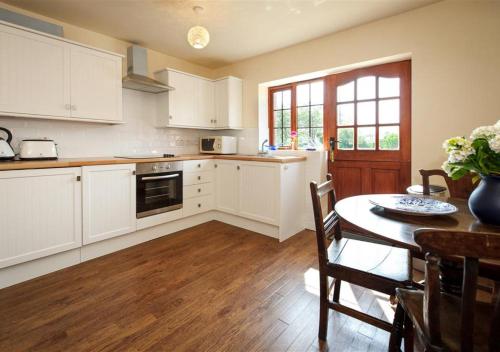 阿伯索赫Y Betws的厨房配有白色橱柜、桌子和用餐室。
