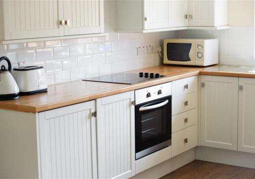 阿伯索赫Y Betws的厨房配有白色橱柜、炉灶和微波炉。