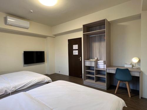 集集镇沐乐旅舍 ML.b&b的酒店客房设有两张床、一张桌子和一台电视。