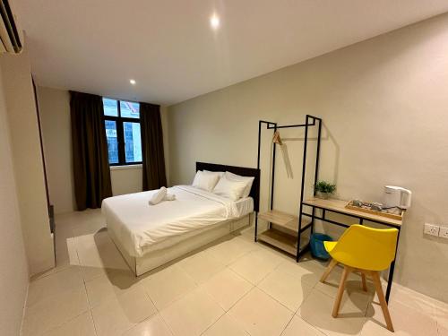 吉隆坡Swing & Pillows - KL Kuchai Lama formerly known as Sunrise Inn的一间卧室配有一张床、一张桌子和一张黄椅