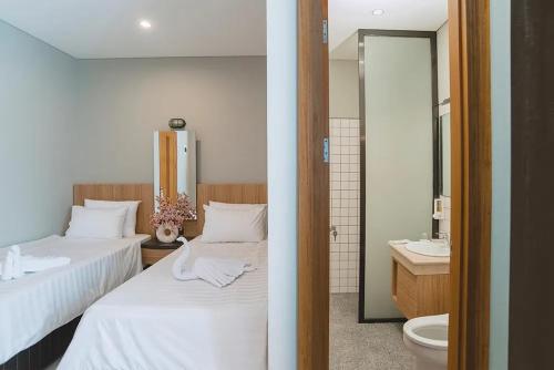 万隆Mogens Guesthouse的一间带两张床的卧室和一间带水槽的浴室