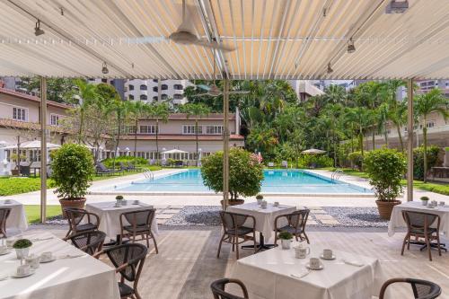 新加坡Goodwood Park Hotel的一间带桌椅的餐厅和一个游泳池