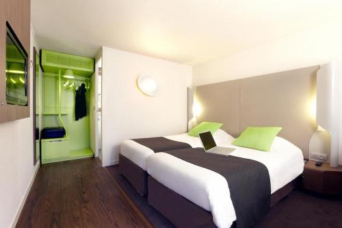 卢瓦尔河畔圣吕斯Hôtel Inn Design Resto Novo Nantes Sainte Luce的酒店客房带两张床和一台笔记本电脑