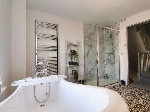 洛斯托夫特First Light的白色的浴室设有浴缸和淋浴。