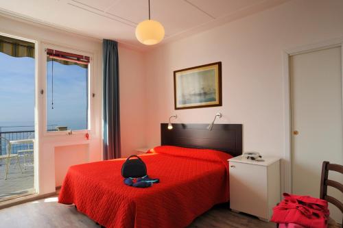 阿拉西奥Hotel Tirreno的一间卧室配有红色的床和红色毯子