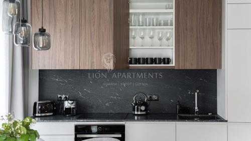 格但斯克Lion Apartments - SCALA City Center Apartments&Studio IIA的厨房配有木制橱柜和黑色台面