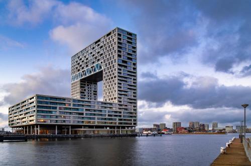 阿姆斯特丹Eric Vökel Boutique Apartments - Riverfront Suites的水体旁边的高楼