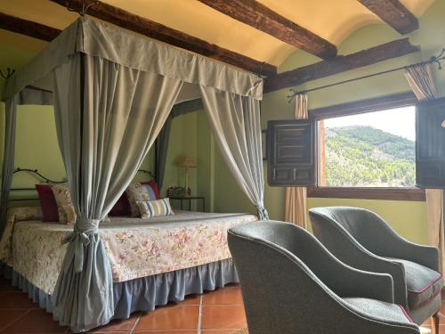 阿尔巴拉辛圣地亚哥之家酒店的一间卧室配有一张天蓬床和两把椅子