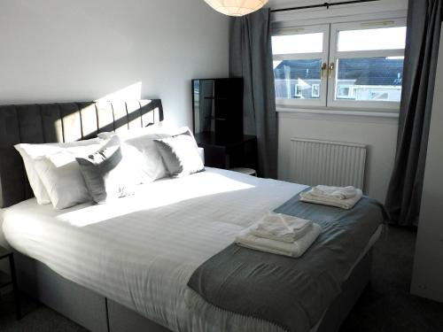 格拉斯哥New & delightful 3 bed house in East Kilbride的一间卧室配有一张大床和两条毛巾