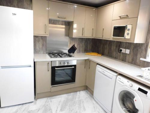 格拉斯哥New & delightful 3 bed house in East Kilbride的厨房配有白色橱柜、洗衣机和烘干机
