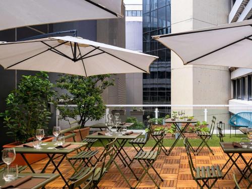 阿格拉泰布里亚恩扎Mercure Milano Agrate Brianza的一个带桌椅和遮阳伞的庭院。