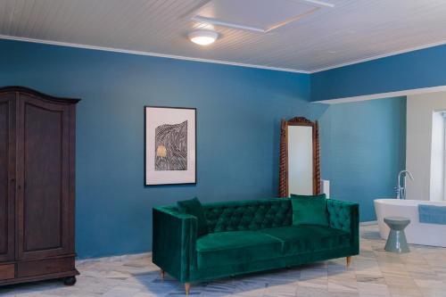 威廉斯塔德Kura Botanica Hotel的客厅设有绿色沙发和蓝色的墙壁