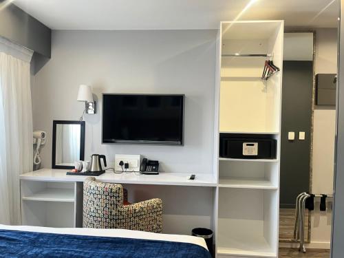 约翰内斯堡ONOMO Hotel Johannesburg Sandton的酒店客房配有一张床和一张书桌及一台电视