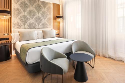 马德里阿托查加泰罗尼亚酒店的一间卧室配有一张大床和一把椅子