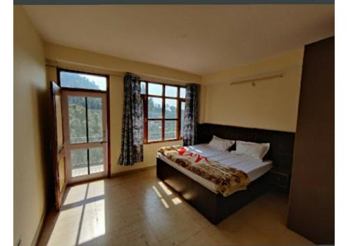 西姆拉Goroomgo Homestay Sukh Dham Shimla - Homestay Like Home Feeling Mountain View的一间卧室设有一张床和一个大窗户