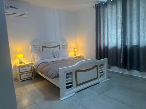 利伯维尔Villa bord de mer louis的一间卧室配有一张白色床、两个床头柜和两盏灯。