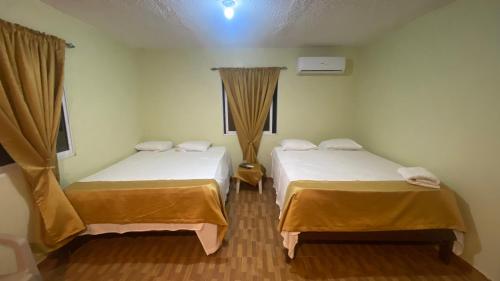 圣塔芭芭拉-山美纳Paraíso de Rojas hotel的客房设有两张床和窗户。