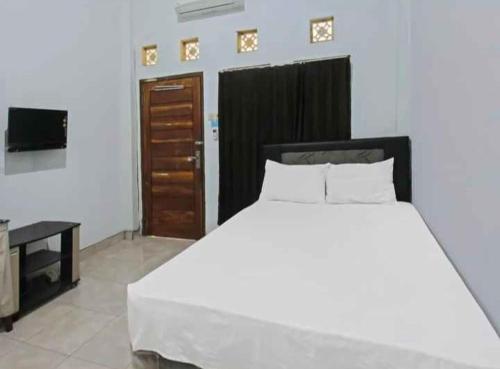 普拉亚Wisma Dhana Syariah的卧室配有一张白色大床和电视。