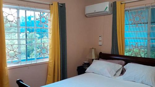 金斯敦Bougainvillea Palms的一间卧室设有床和黄色窗帘的窗户