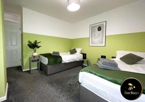 CrontonBee Stays - Afton House的绿墙客房内的两张床